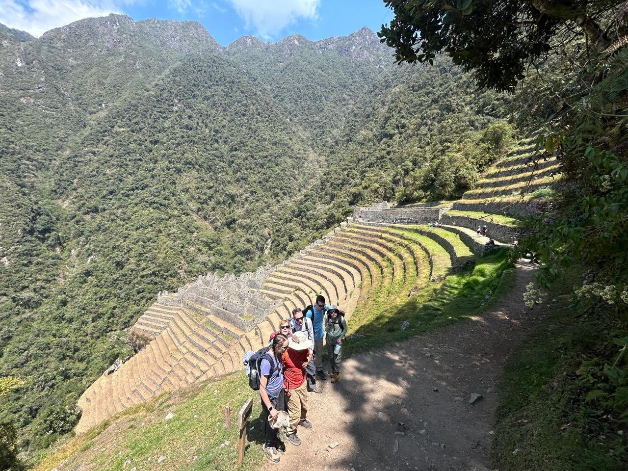 Grupo de caminhantes junto aos terraços incas de Wiñay Wayna, entre montanhas cobertas de vegetação