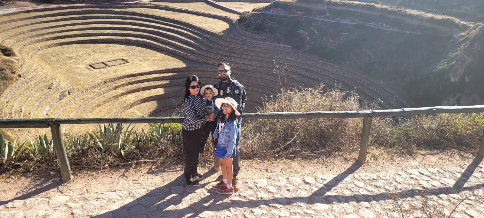 Família diante dos terraços circulares de Moray, no Vale Sagrado do Peru
