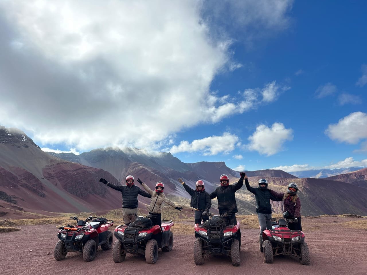 Viajantes com capacetes e quadriciclos no percurso de Vinicunca e Vale Vermelho.