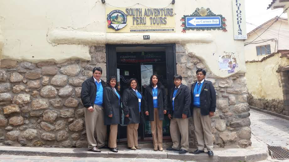 Registro histórico da equipe local da South Adventure Peru Tours em frente ao escritório, com o letreiro da empresa.